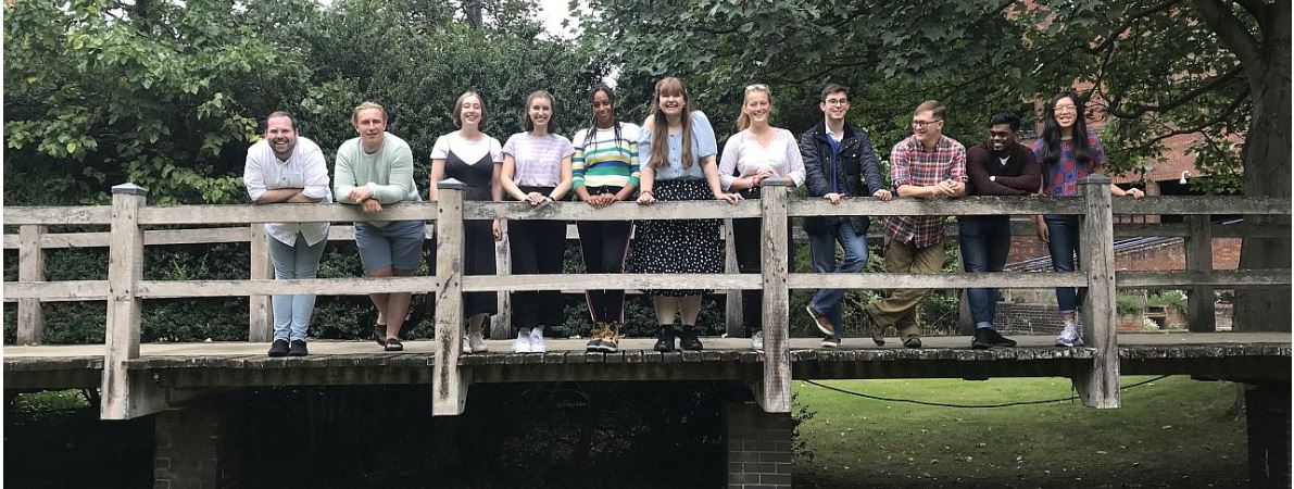 A group of student callers from the 2019 Telephone campaign standing on the bridge over the brook in the college gardens